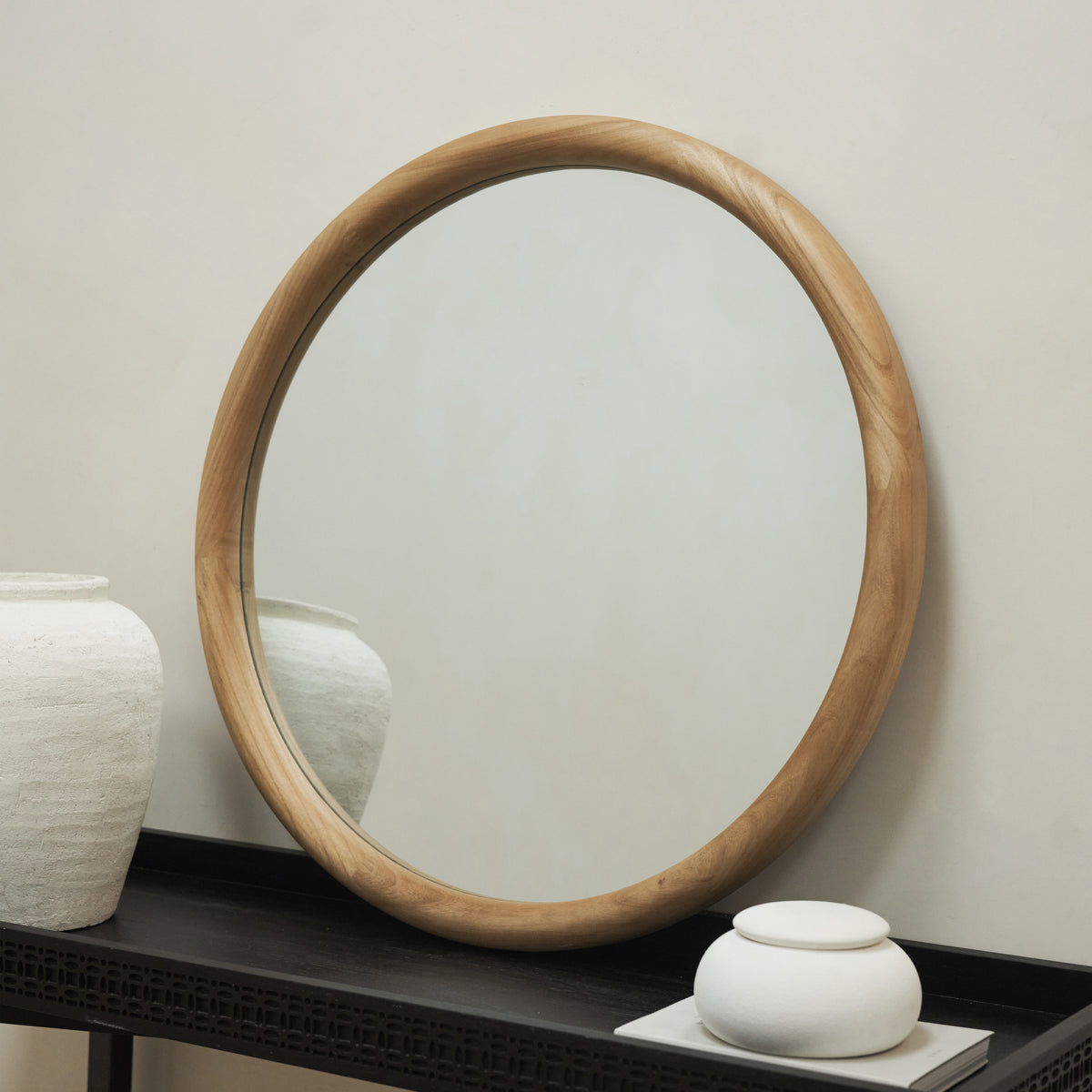 Our Natural Round Wall Mirror leaning against a wall