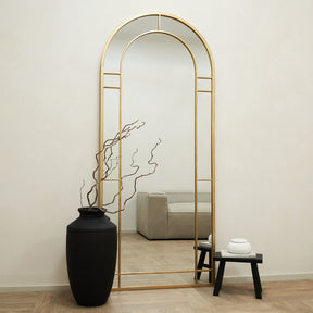 Gold Industrial Full Length Arched Metal Mirror leaning against wall