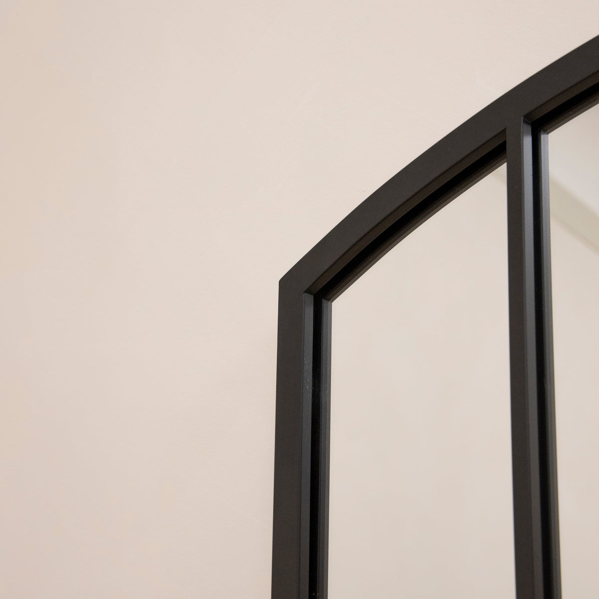 Closeup of Full length black metal window mirror arch