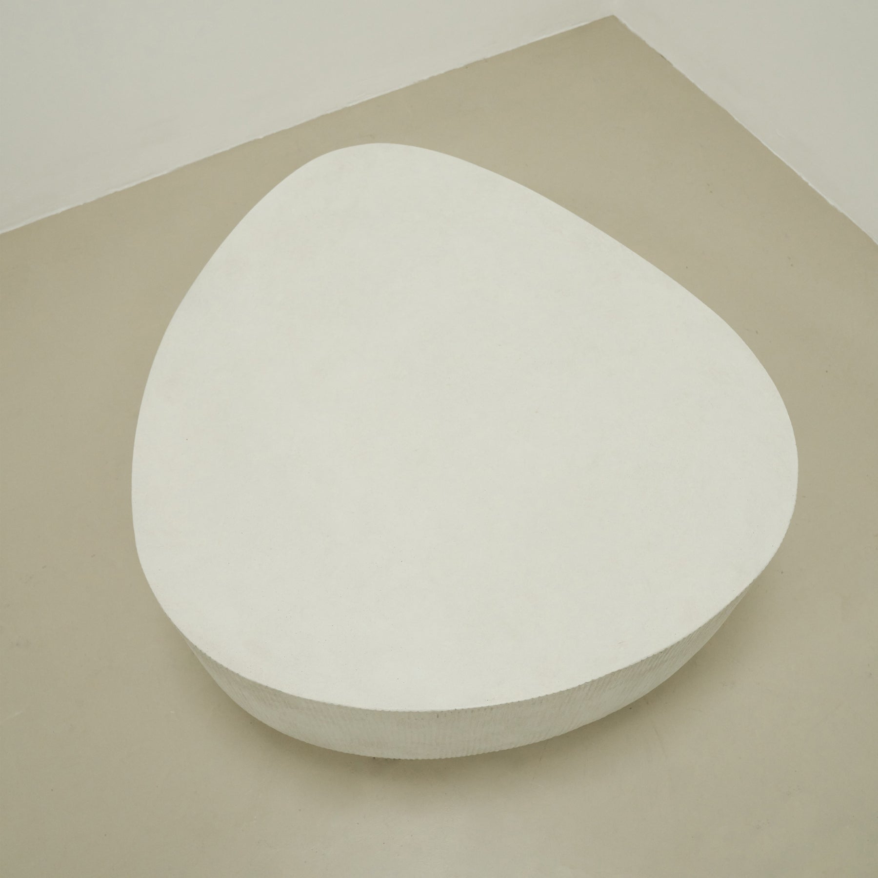 Top-down view of Minimal Concrete Irregular Shaped Coffee Table Large in muted room, empty
