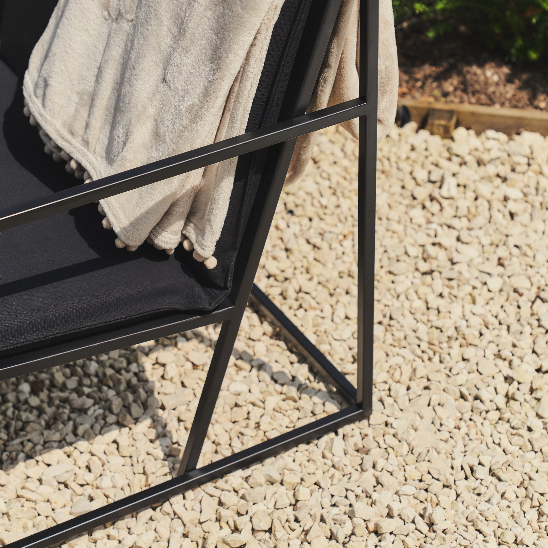 Detail shot of Rounded Black Modern Garden Chair on gravel