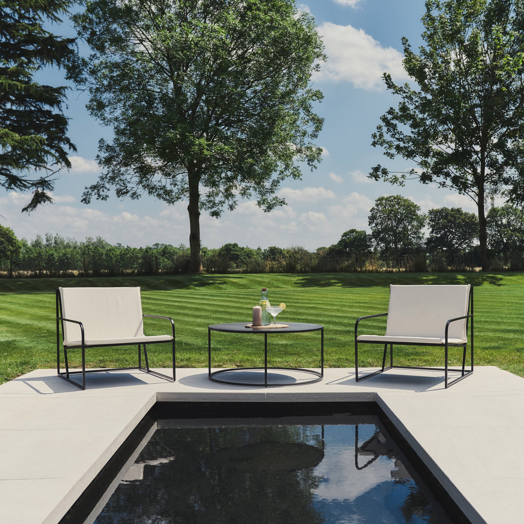 Wide shot of select pieces of our Sand Modern Rounded Garden Furniture Set beside a pool