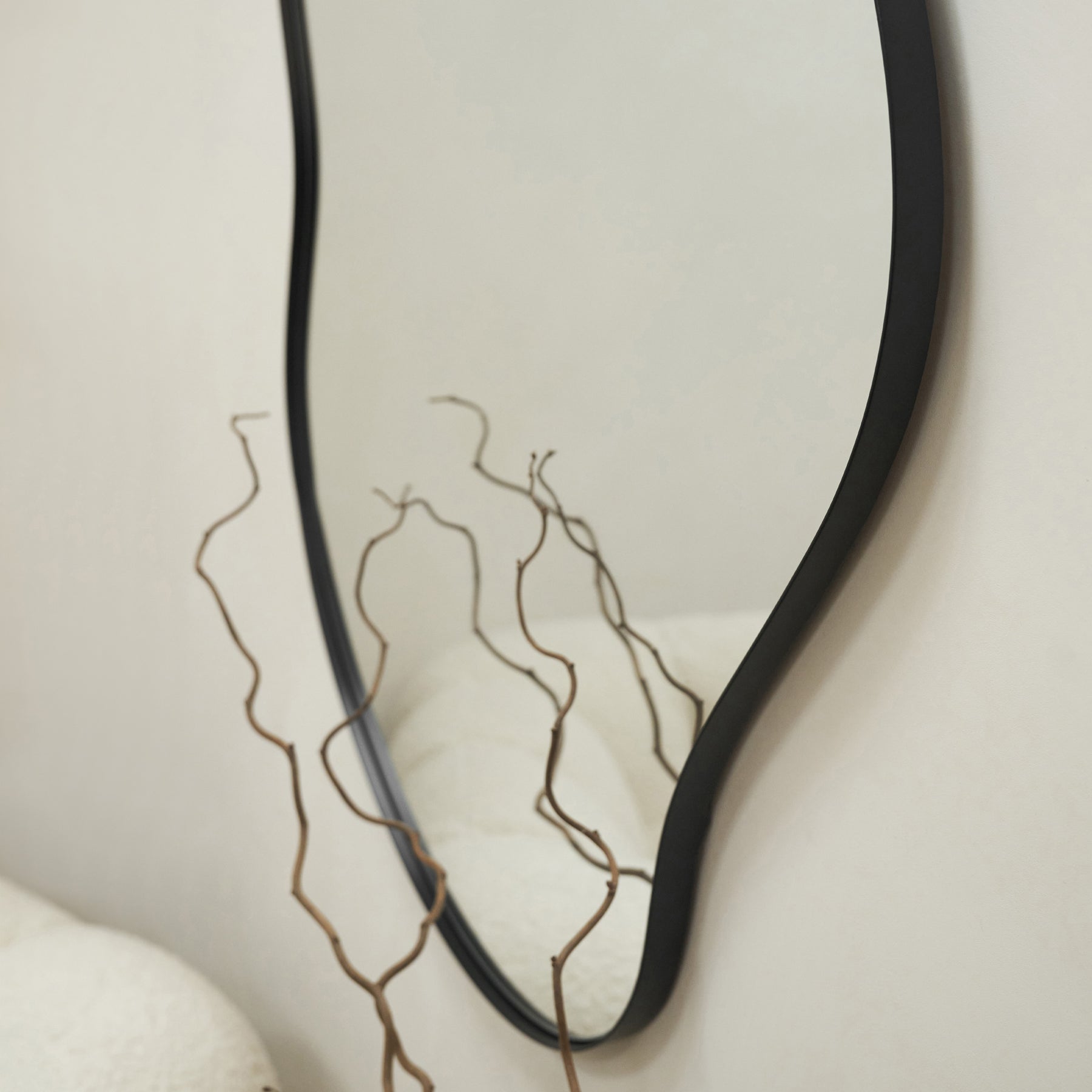 Black Metal Pond Shaped Irregular Wall Mirror on wall above branches